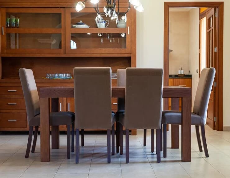 Eetkamer met massief houten tafel en zes grijs gestoffeerde stoelen