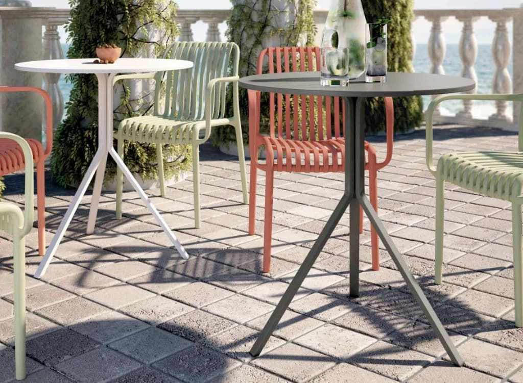 Terras aan zee met ronde tafels en tuinstoelen in groen en terracotta